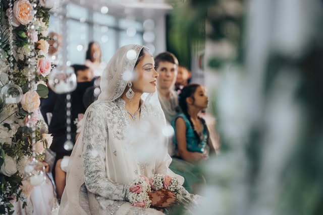 Bride in silver-embroidered ivory, florals and hanging crystals in the foreground